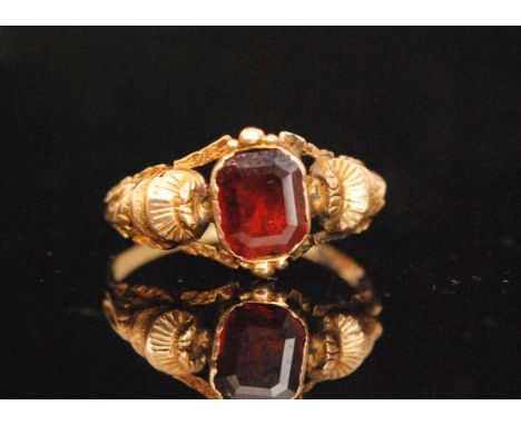 A Georgian yellow gold and garnet ring, the emerald flat cut garnet with closed back setting, pierced shoulders with tiered s