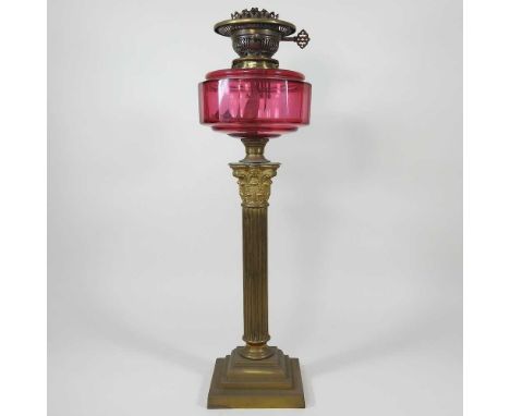 A brass corinthian column oil lamp base, with cranberry glass font, 57cm highGererally dirty and the metal is very dull. Ther