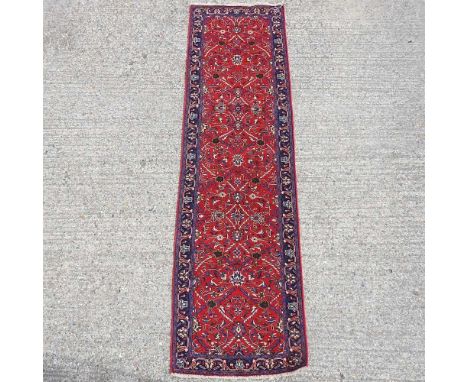 A Sarouk runner, with foliate design, on a red ground, 307 x 84cm