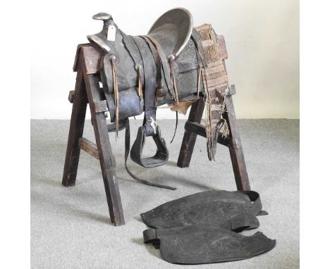 A western style tooled leather saddle, on stand, 77cm highOverall worn and dirty. Looks to be mostly complete although quite 