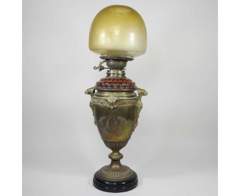 A brass oil lamp, surmounted by eagle heads, with amber coloured glass reservoir and shade, 59cm highDirty with general wear 