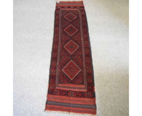 A Persian runner, with a row of four central medallions, on a red ground, 251 x 66cm