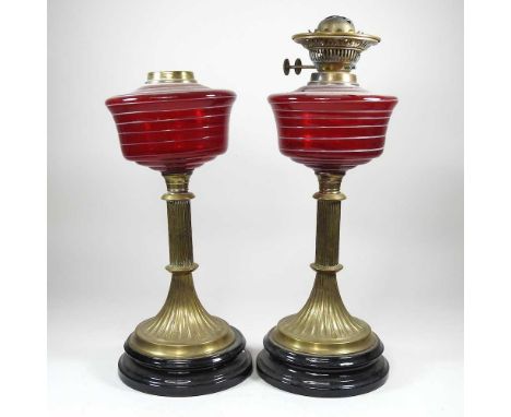 A near pair of oil lamps, with ruby and white striped glass reservoirs, highest 47cm