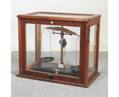 A set of early 20th century balance scales, bearing a label for Brady &amp; Martin Ltd, in a glazed case, 47cm wide