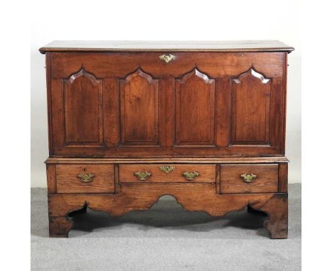 An 18th century oak coffer on stand, with a hinged lid and adapted fall front, with drawers below, on bracket feet, with copy