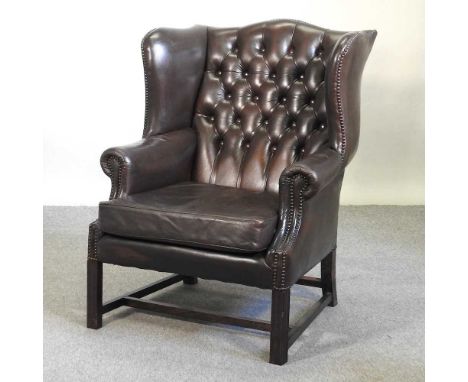 A brown upholstered wingback armchair, with a button back, on square legs