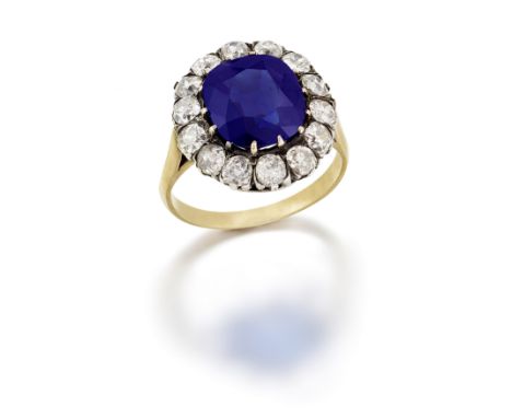 SAPPHIRE AND DIAMOND CLUSTER RINGThe cushion-shaped sapphire, weighing 5.493 carats, within a surround of similarly-shaped an