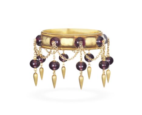 GOLD AND GARNET-SET ARCHAEOLOGICAL REVIVAL BANGLE, CIRCA 1860Set with a series of garnet cabochons, issuing a fringe of garne