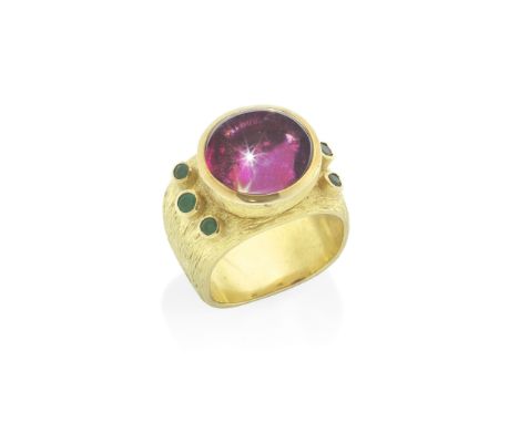 GRIMA: GARNET AND EMERALD DRESS RINGThe oval cabochon garnet collet-set within a textured geometric mount, between circular-c