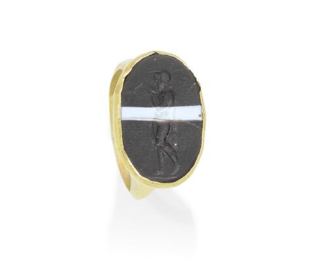 PASTE INTAGLIO RINGThe oval paste simulating banded agate, carved to depict a standing nude figure drinking from a cup, ring 