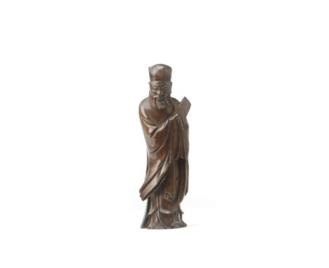 A HARDWOOD CARVING OF AN OFFICIAL17th/18th centuryThe bearded figure wearing a hat and flowing belted robes with voluminous s
