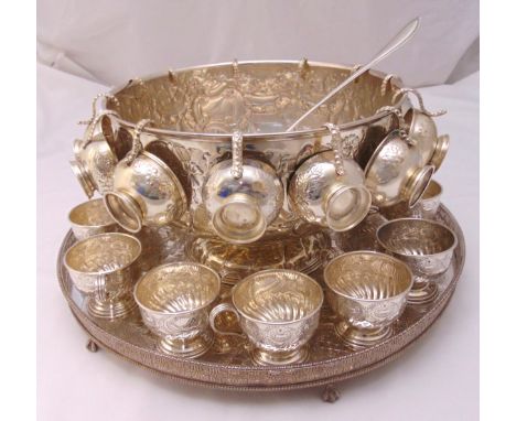 A silver plated punch bowl chased with flowers and leaves with twenty five cups and a punch ladle with beaded border all on a