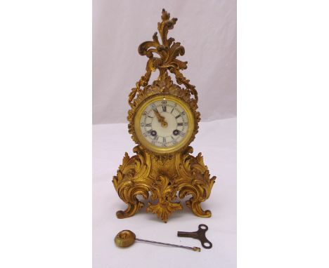 A French 19th century ormolu mantle clock, the rococo case with circular enamel dial and Roman numerals all on four scroll le