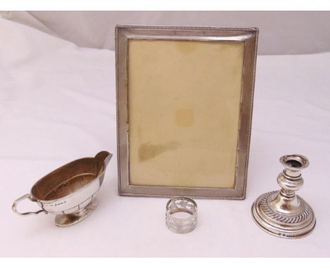 Four pieces of hallmarked silver to include a sauce boat, photograph frame, a napkin ring and a candlestick (4)