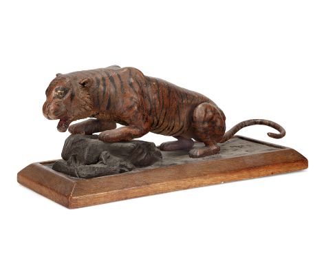 A stuccoed wood figure of a tiger,First half 20th century,Crouching, his forelegs resting on a rock, on plinth36cm. long, 15.