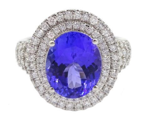 18ct white gold oval tanzanite and two row round brilliant cut diamond cluster ring, with diamond set shoulders, stamped 750,