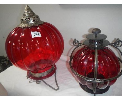 A red glass and metal hanging shade together with a red glass and metal candle lantern,.