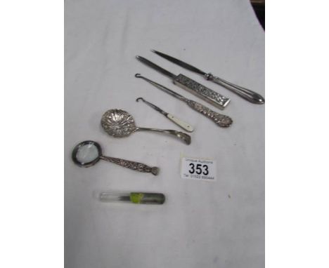 2 letter openers, 2 button hooks, a magnifying glass and a needle case.