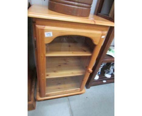 A pine 3 shelf cabinet with glass door.