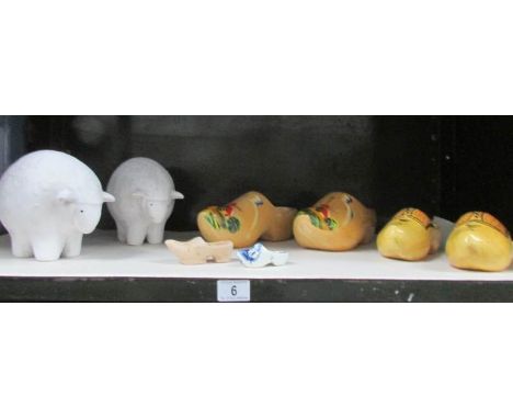 A shelf of miscellaneous items including wooden clogs, figures of sheep etc.,