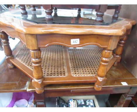 A glass topped coffee table with cane under shelf.