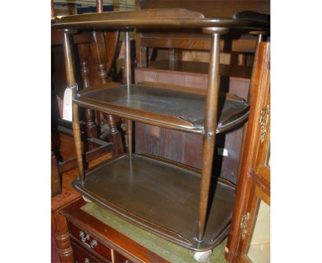 An Ercol dark elm three tier tea trolley on roller casters