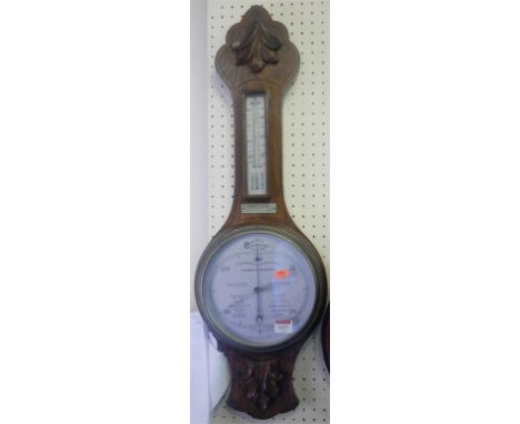 A mid-20th century carved oak two dial aneroid wheel barometer 