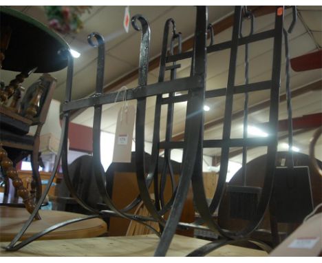 A contemporary black painted wrought iron log basket of open form with four various hanging fire tools