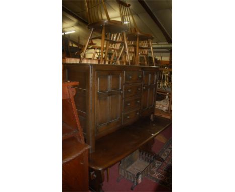 An Ercol dark elm dining suite comprising; dining table, six stickback dining chairs, and a sideboard (8)