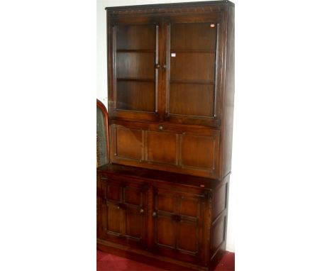 A contemporary Ercol dark elm bookcase cupboard, having central fall-front 