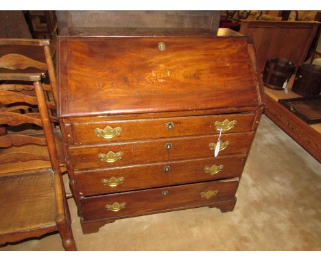 A George III elm and oak bureau with four graduated drawers, brass escutcheons and handles (one present but detached), the fa