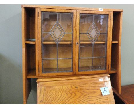 A light oak floor standing lead glazed two door display cabinet flanked by narrow shelves