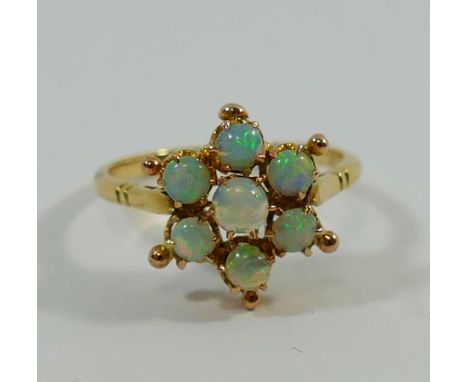 A yellow metal opal cluster ring, the seven round opal cabochons in claw set daisy head arrangement, finger size N, 2.1g gros