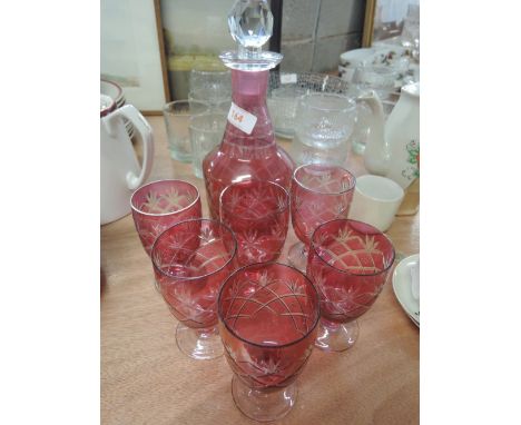 A cranberry style cut glass decanter and six glasses