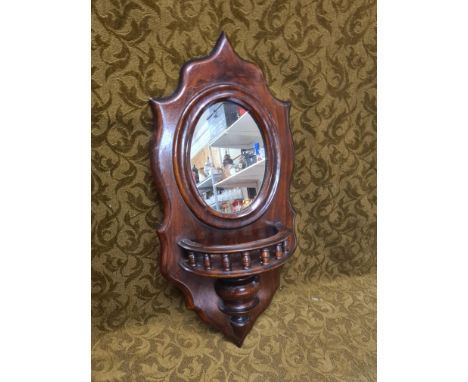 A late Victorian mahogany wall bracket with gallery shelf and oval mirror, 51cm.