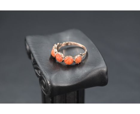 A yellow metal ring having five carved circular coral panels in collared mounts on a rose gold coloured loop, no marks, size 