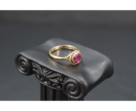 A ruby ring having a facet cut circular stone in a collared mount on a 9ct gold loop, size O/P &amp; approx 2.9g