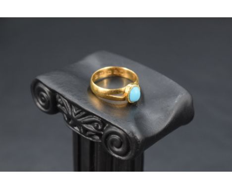 A Victorian 22ct gold ring having small oval turquoise cabochon in collared mount to split shoulders on 22ct gold loop, size 