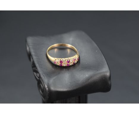 A ruby and diamond ring having a double row of alternate diamond &amp; ruby chips in a claw set mount to moulded shoulders on
