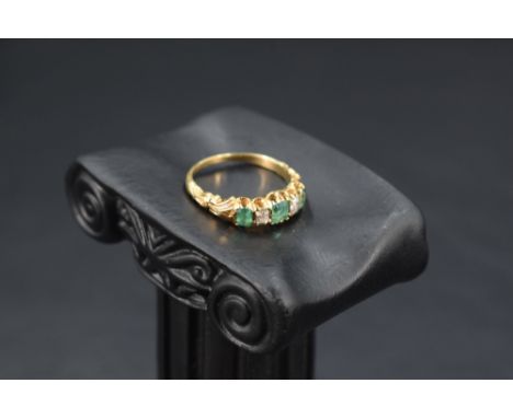 A Victorian diamond and emerald five stone ring having three baguette cut emeralds and two old cut diamonds in a gallery moun