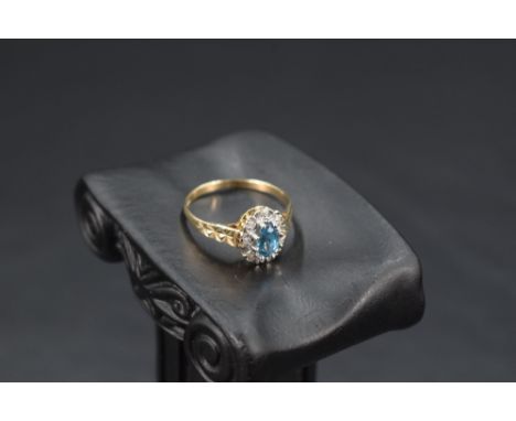 A blue topaz  and diamond chip cluster ring having an illusionary mount to cut shoulders on a 9ct gold loop, size P &amp; app