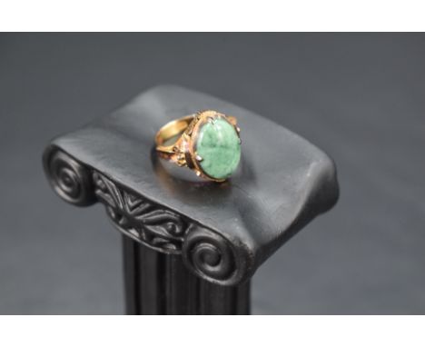 An oval jade cabochon ring in a four claw collared mount on a Chinese gold loop, size K and approx 4.6g