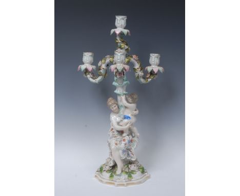 A Continental porcelain figural four-light candelabrum, acanthus moulded sconces, flower encrusted branches, the shaped circu