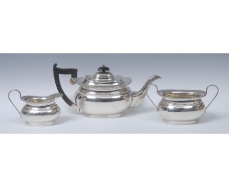 A George V silver three piece boat shaped tea service, comprising teapot, milk jug and sugar basin, hinged cover with knop fi