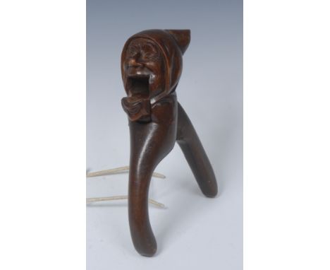 A Black Forest lever action novelty nut cracker, carved as the head of a gentleman in a cloth cap, 22cm long, c.1900