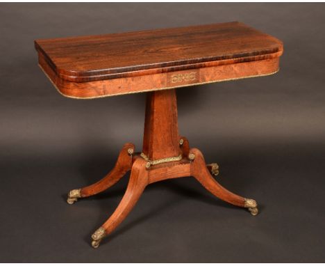A Regency rosewood rounded rectangular card table, hinged folding top with baize playing surface, applied with gilt metal scr
