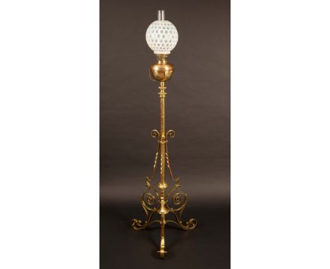 A Victorian brass floor standing extending oil lamp, globular uranium shade , brass reservoir, the column with three scroll b