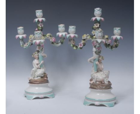 A pair of 19th century Continental four branch, three light figural candelabra, the arms encrusted with roses, the columns su