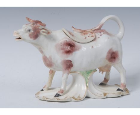 A Derby creamer and cover, in the form of a horned cow, standing on all four, rust patch markings, shaped base, 10cm high, c.