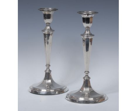 A pair of George V silver table candlesticks, detachable nozzles, panelled campana sconces, tapered pillars and spreading bas